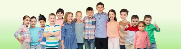 Grupo de niños sonrientes felices abrazándose sobre verde — Foto de Stock