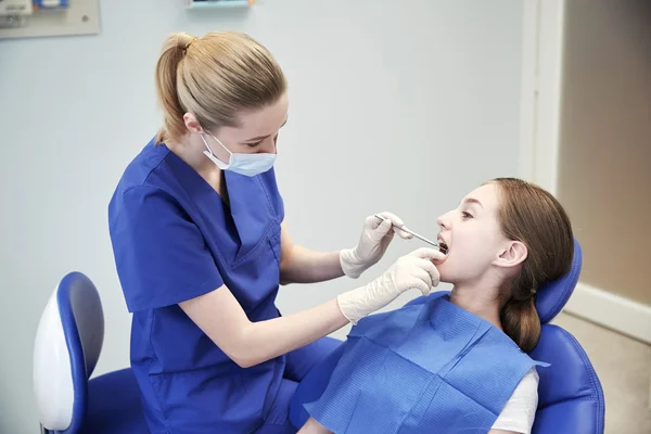 Dentista feminino verificando os dentes da menina paciente — Fotografia de Stock