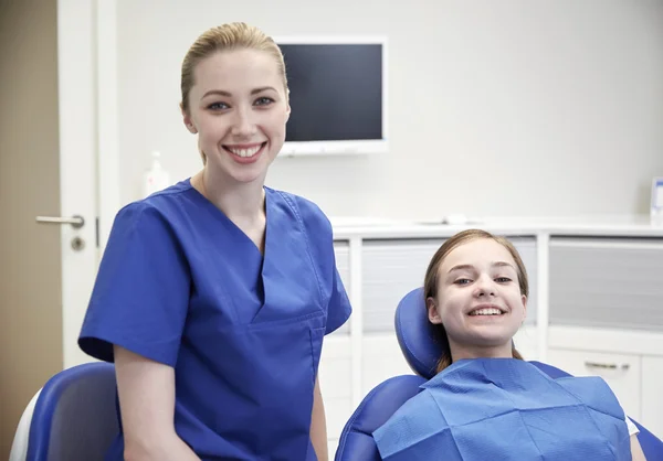 Szczęśliwa kobieta dentysty z dziewczyna pacjenta w klinice — Zdjęcie stockowe