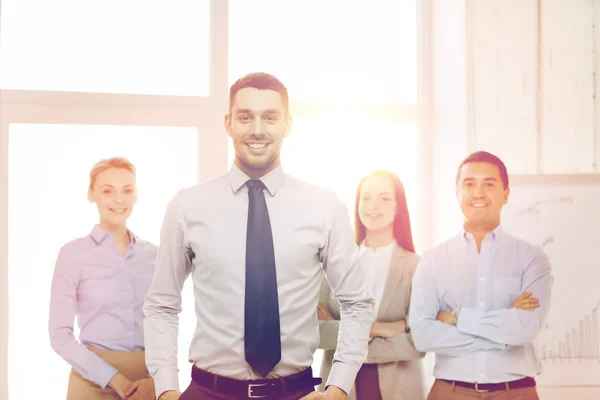 Hombre de negocios sonriente en la oficina con el equipo en la espalda — Foto de Stock