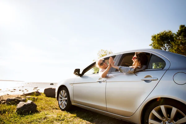 Happy teenage girls or women in car at seaside — Stock Photo, Image