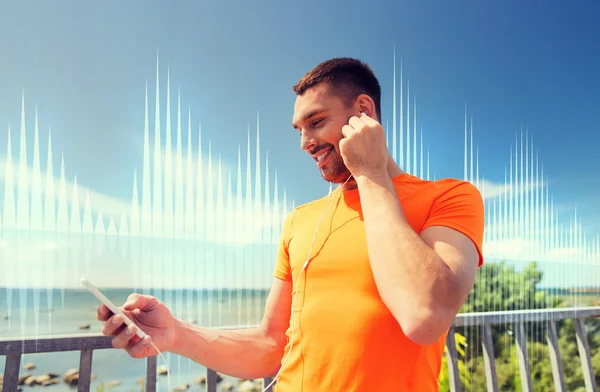 Smiling young man with smartphone and earphones — Stock Photo, Image