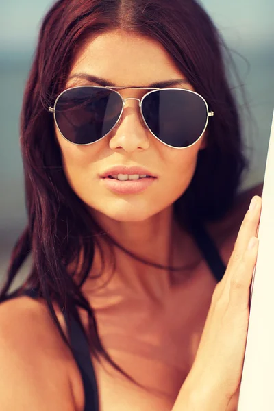 Smiling young woman with surfboard on beach — Stock Photo, Image