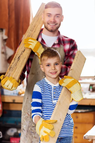 Happy father and son with wood plank at workshop — Stock Photo, Image