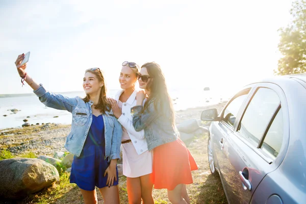Mujeres felices tomando selfie cerca de coche en la playa —  Fotos de Stock