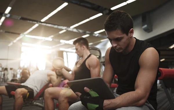 Groep van mannen met tablet pc en halters in gym — Stockfoto