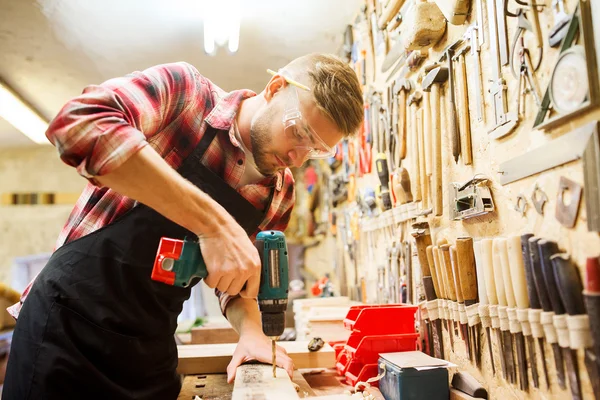 Timmerman met boor boren plank op workshop — Stockfoto