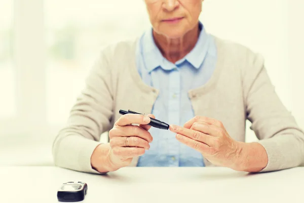 Пожилая женщина с глюкометром проверяет уровень сахара в крови — стоковое фото