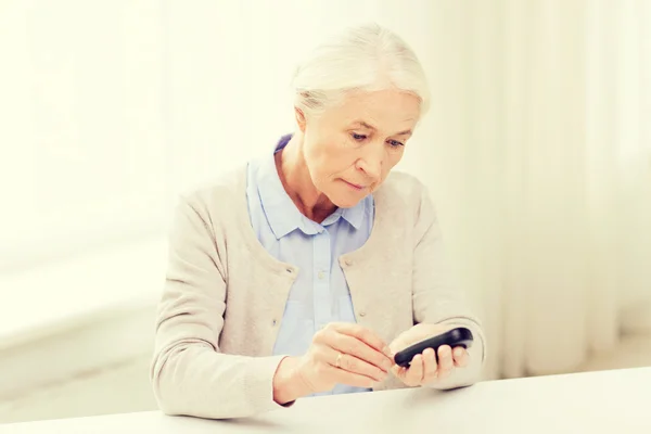 Senior vrouw met glucometer controleren bloedsuikerspiegel — Stockfoto