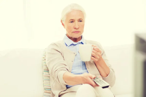 Anziana donna guardando la tv e bevendo tè a casa — Foto Stock