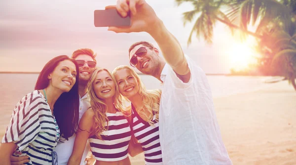 Amigos felices tomando selfie por teléfono inteligente en la playa —  Fotos de Stock