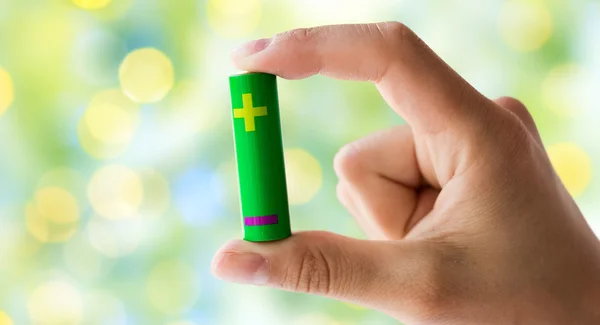 Close up of hand holding green alkaline battery — Stock Photo, Image