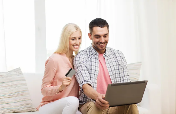 Feliz pareja con ordenador portátil y tarjeta de crédito en casa —  Fotos de Stock