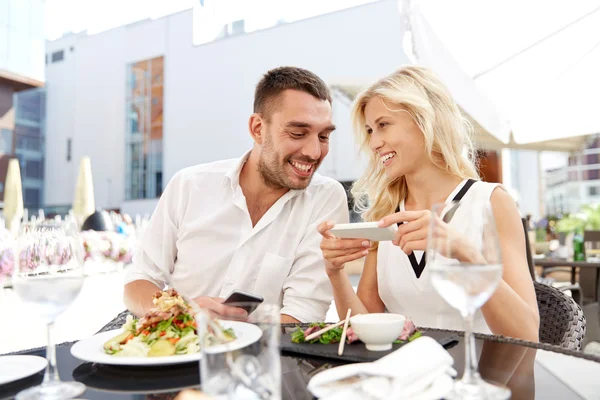 Счастливая пара со смартфоном на террасе ресторана — стоковое фото