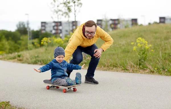 Šťastný otec a malý syn, ježdění na skateboardu — Stock fotografie