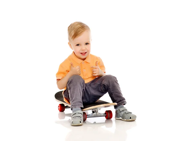 Щасливий маленький хлопчик на скейтборді показує великі пальці вгору Стокове Фото