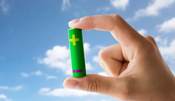 Close up of hand holding green alkaline battery — Stock Photo, Image