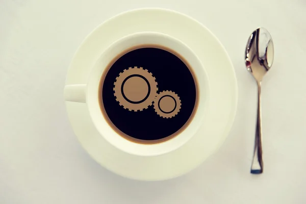 Cup of coffee with cogwheel symbol and spoon — Stock Photo, Image