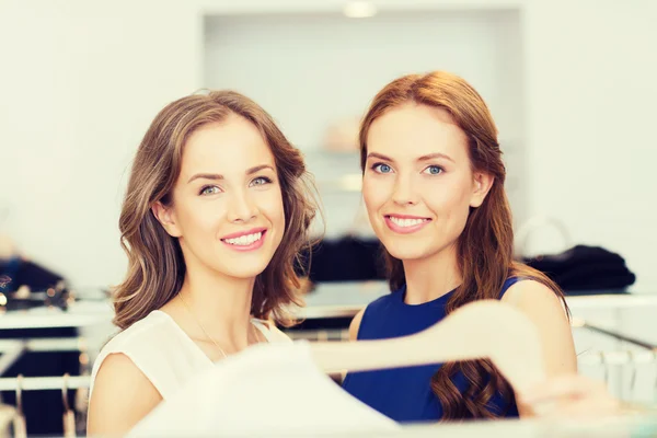 Glada kvinnor med shoppingväskor i klädaffär — Stockfoto
