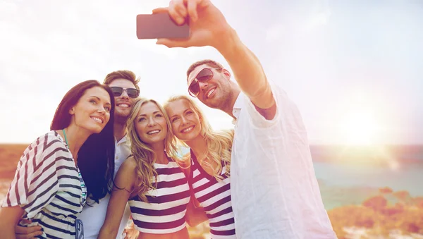 Amigos felices tomando selfie por teléfono inteligente en la playa — Foto de Stock