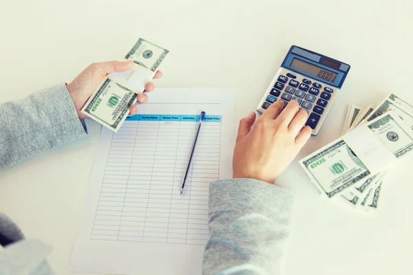 Fechar as mãos contando dinheiro com calculadora — Fotografia de Stock