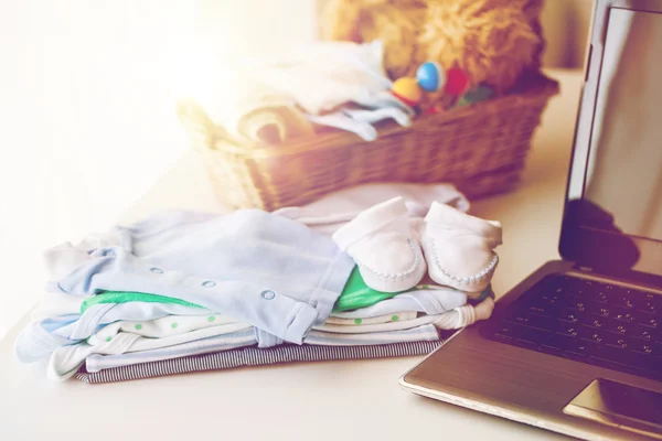 Zbliżenie ubrań dla niemowląt, zabawek i laptopów — Zdjęcie stockowe