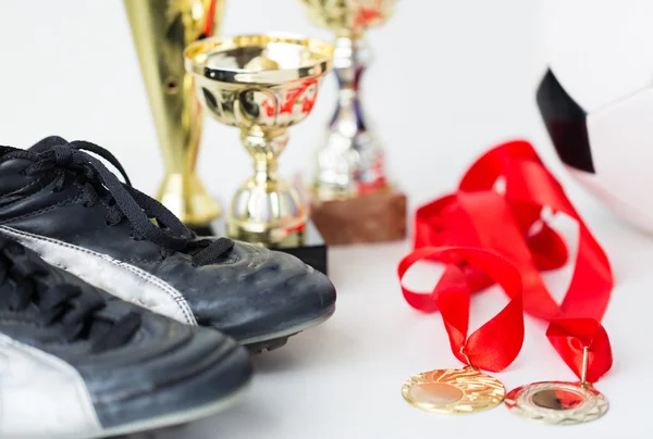 Close-up van voetbalschoenen, kopjes en medailles — Stockfoto