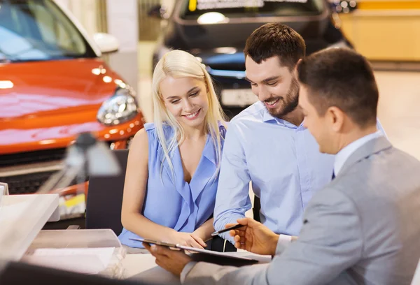 Happy couple with car dealer in auto show or salon — Stock Photo, Image