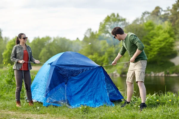 Happy couple setting up tent outdoors Royalty Free Stock Images