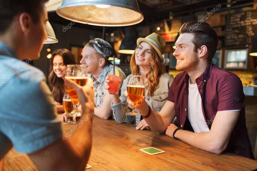 Happy Friends With Drinks Talking At Bar Or Pub — Stock Photo © Syda