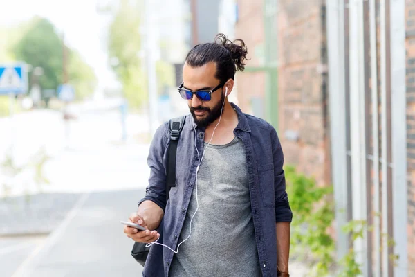 Hombre con auriculares y smartphone caminando en la ciudad — Foto de Stock