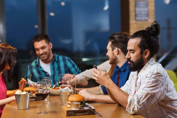 Ο άνθρωπος με το smartphone και τους φίλους σας στο εστιατόριο — Φωτογραφία Αρχείου