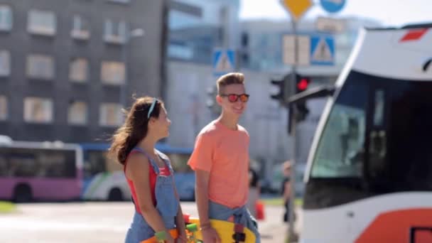 Tiener paar met penny planken lopen in de stad — Stockvideo