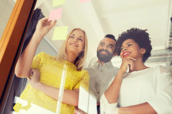 Feliz equipo creativo escribiendo en pegatinas en la oficina — Foto de Stock