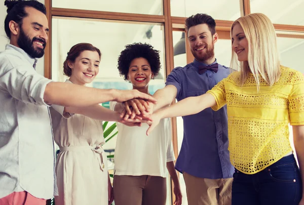 Heureux équipe créative ith mains sur le dessus dans le bureau — Photo