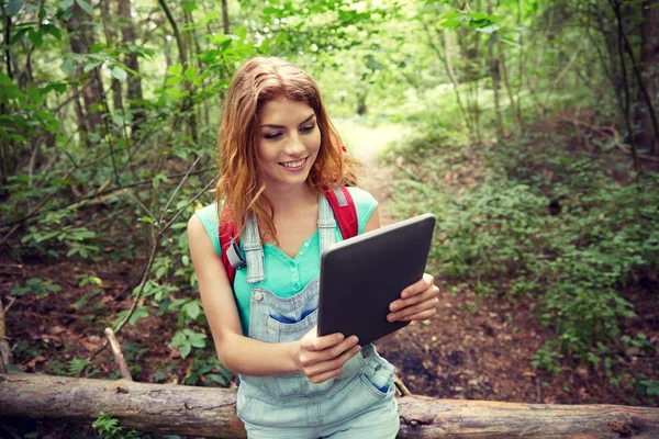 Gelukkige vrouw met rugzak en tablet pc in bos — Stockfoto