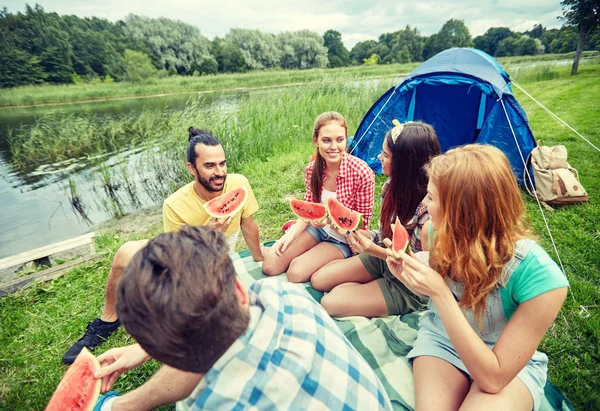 Amigos felizes comendo melancia no acampamento — Fotografia de Stock