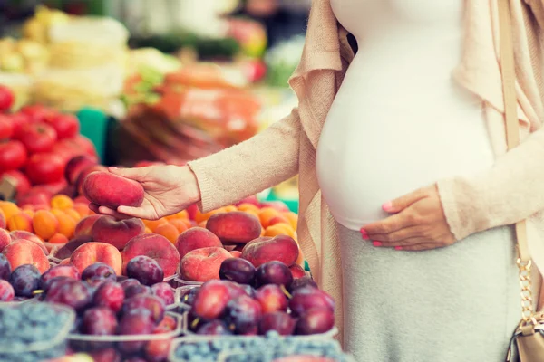 Mulher grávida escolhendo frutas no mercado de rua — Fotografia de Stock