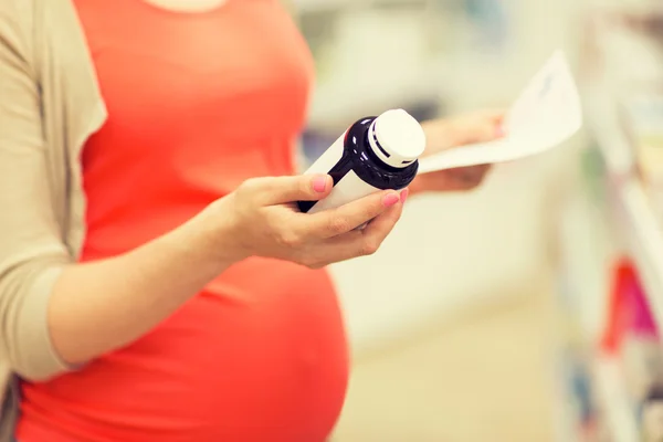 Mulher grávida com frasco de medicação na farmácia — Fotografia de Stock