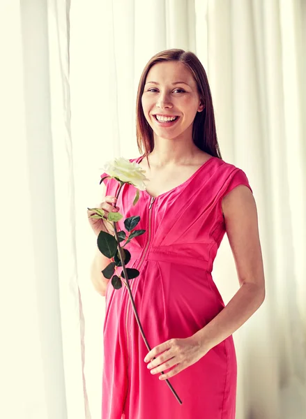 Mujer embarazada feliz con flor de rosa en casa — Foto de Stock