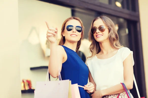 Mujeres jóvenes felices con bolsas de compras en el centro comercial —  Fotos de Stock