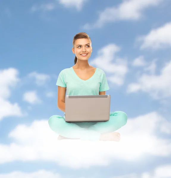 雲の上に座ってラップトップを持つ幸せな若い女性 — ストック写真