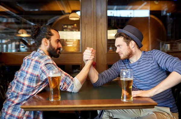 Hombres que beben cerveza y luchan con los brazos en un bar o pub — Foto de Stock