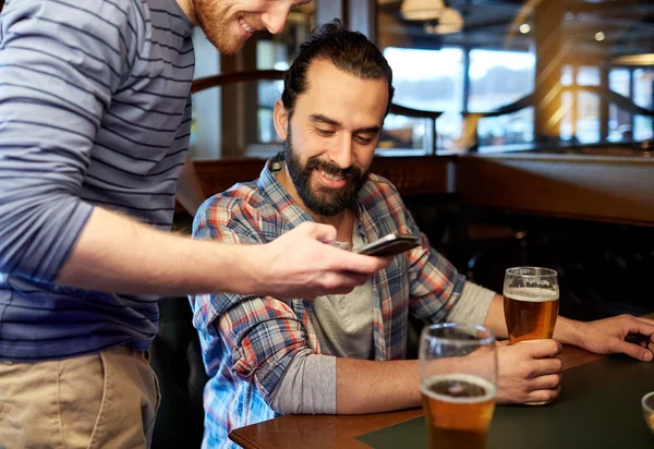 Homens com smartphones bebendo cerveja no bar ou pub — Fotografia de Stock