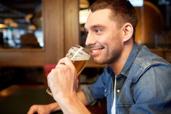 Homem feliz bebendo cerveja rascunho no bar ou pub — Fotografia de Stock