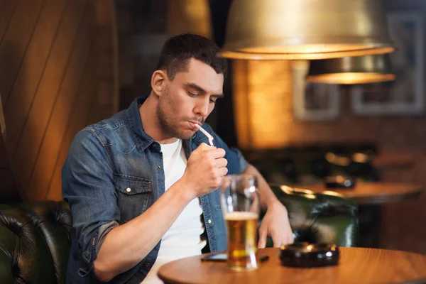 Mann trinkt Bier und raucht Zigarette an Bar — Stockfoto