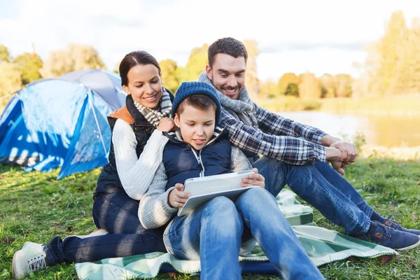 Счастливая семья с планшетным компьютером и палаткой на территории лагеря — стоковое фото