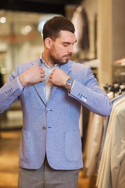 Молодой человек примеряет куртку в магазине одежды — стоковое фото