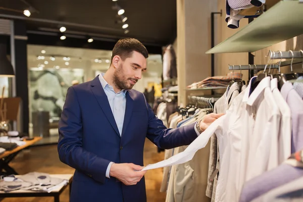 Gelukkig jonge man kiezen kleren in kledingwinkel — Stockfoto