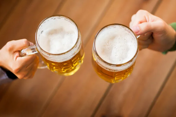 Primo piano delle mani con boccali di birra al bar o pub — Foto Stock